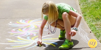 ein Schulkind malt mit Straßenkreide