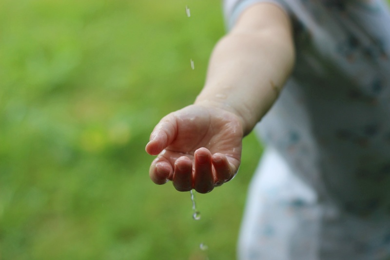 Eine Kinderhand fängt Wasser auf.